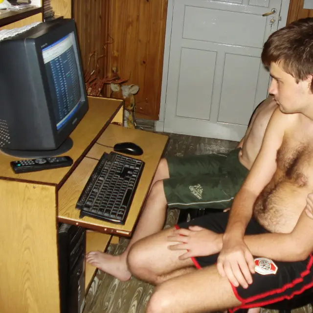 Chico concentrado mirando la pantalla de una computadora con monitor de tubo