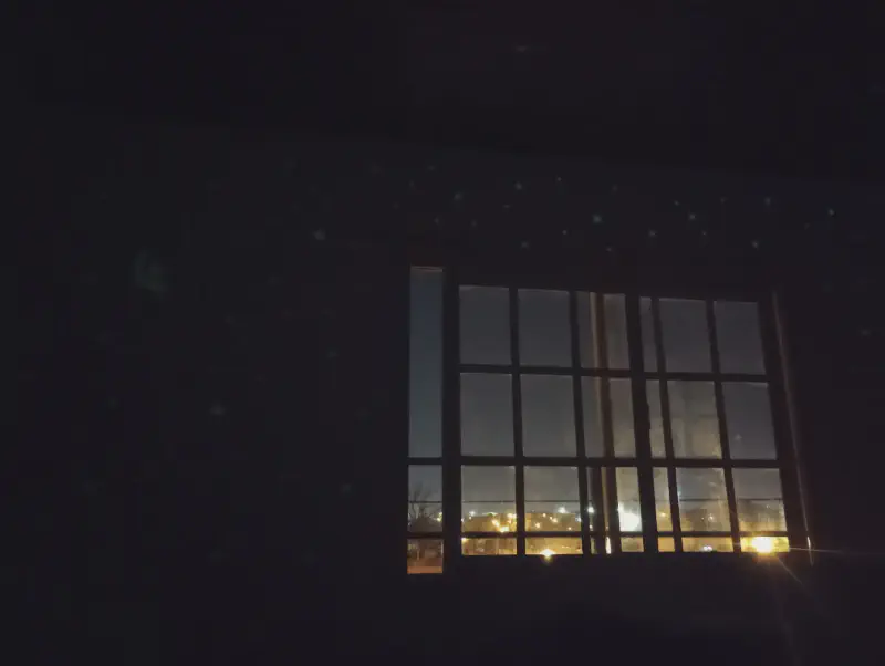 Pieza oscura con una ventana iluminada y las luces de afuera