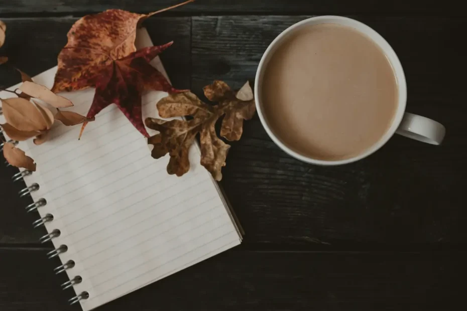 A notebook with dry leaves on top, and a tea mug next to it