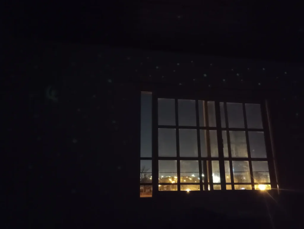pieza oscura con una ventana iluminada y las luces de afuera