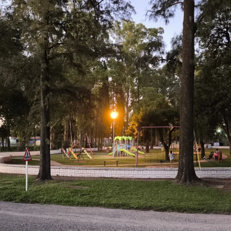 Atardecer en la plaza, donde un farol amarillo brilla exactamente en el lugar donde estaría el sol