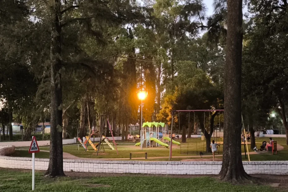 Atardecer en la plaza, donde un farol amarillo brilla exactamente en el lugar donde estaría el sol